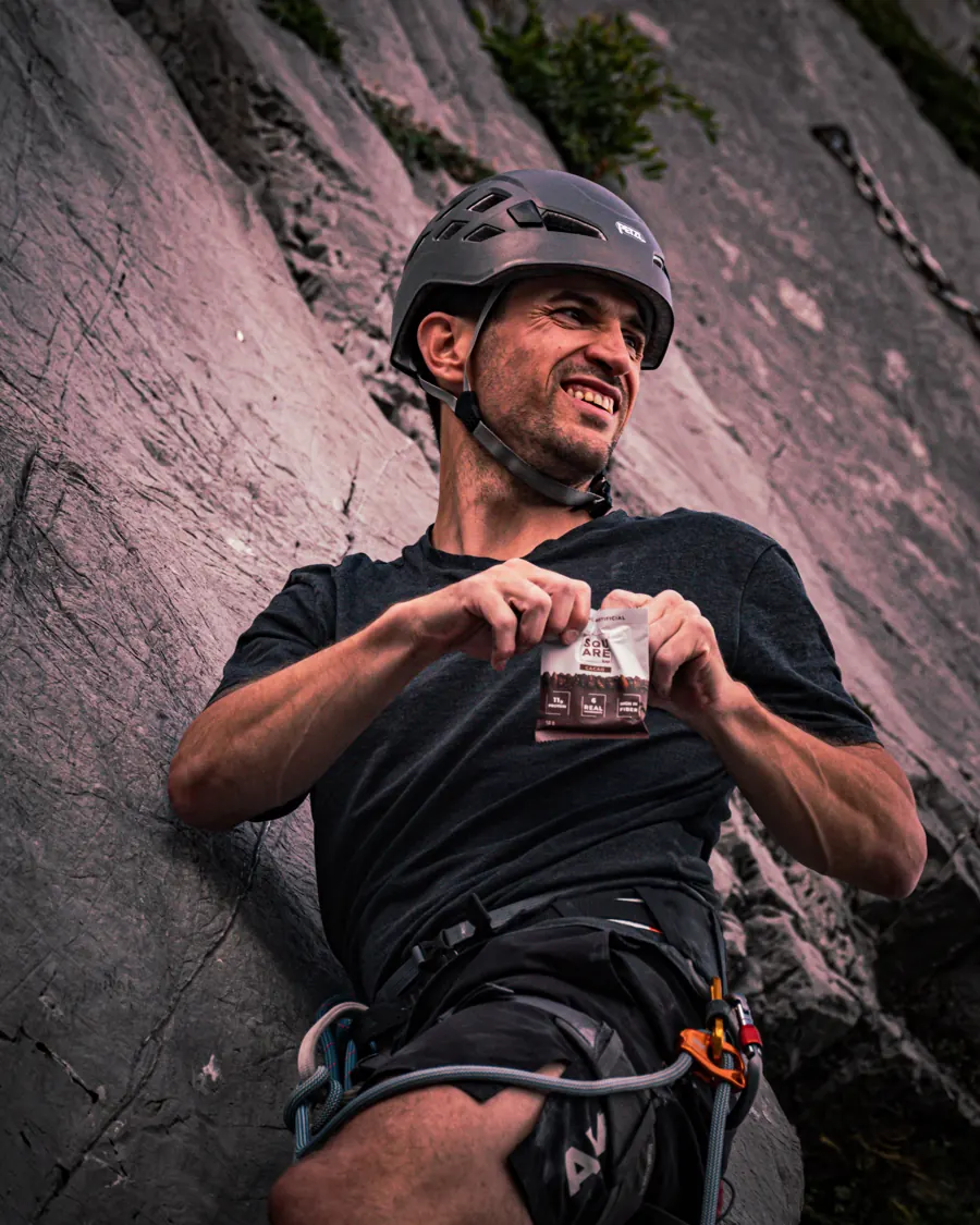Pause mitten in der Kletterroute, ein Riegel von The Square Bar in der Hand